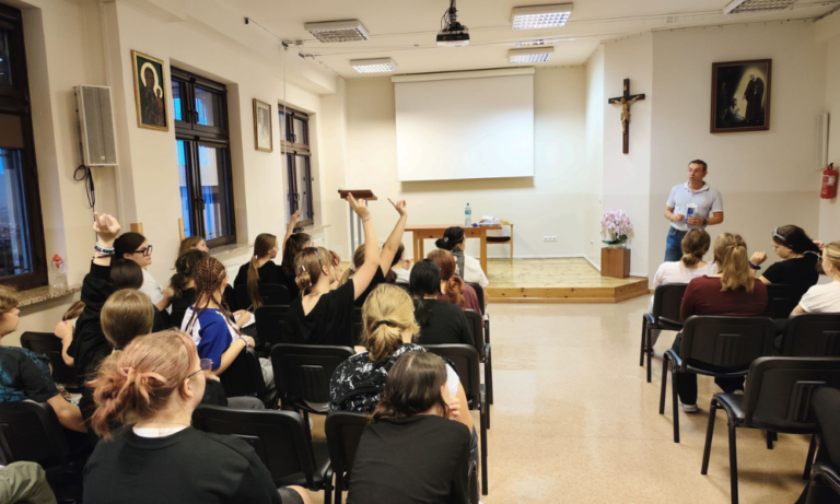 Młodzież podnosi ręce, odpowiadając na pytanie Przemysława Łojka