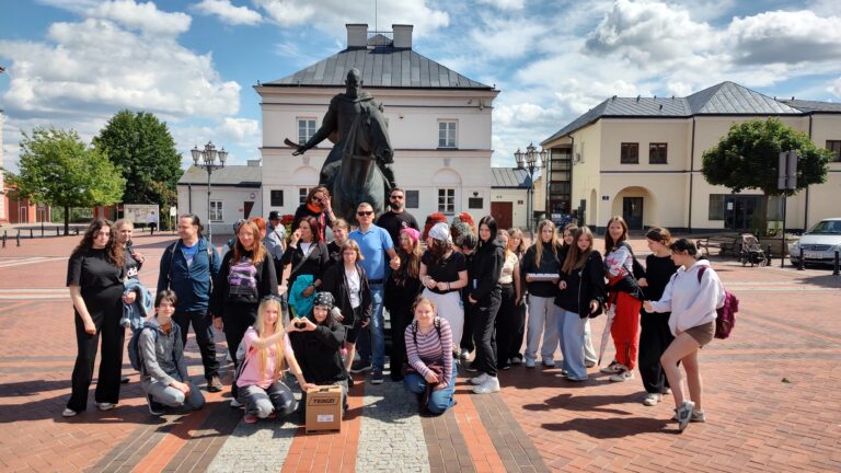 Wspólne zdjęcie uczestników gry miejskiej przed pomnikiem na rynku w Warce